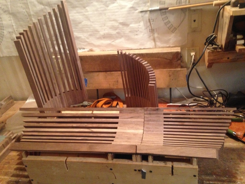Walnut tine assemblies standing vertically in the workshop, showing curved forms